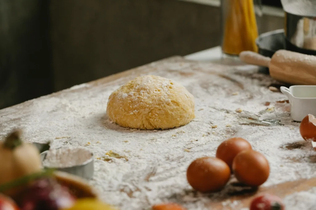 Ce este drojdia alimentara și cum se folosește drojdia alimentară. Aluat de pâine dospit pe masă cu făină.